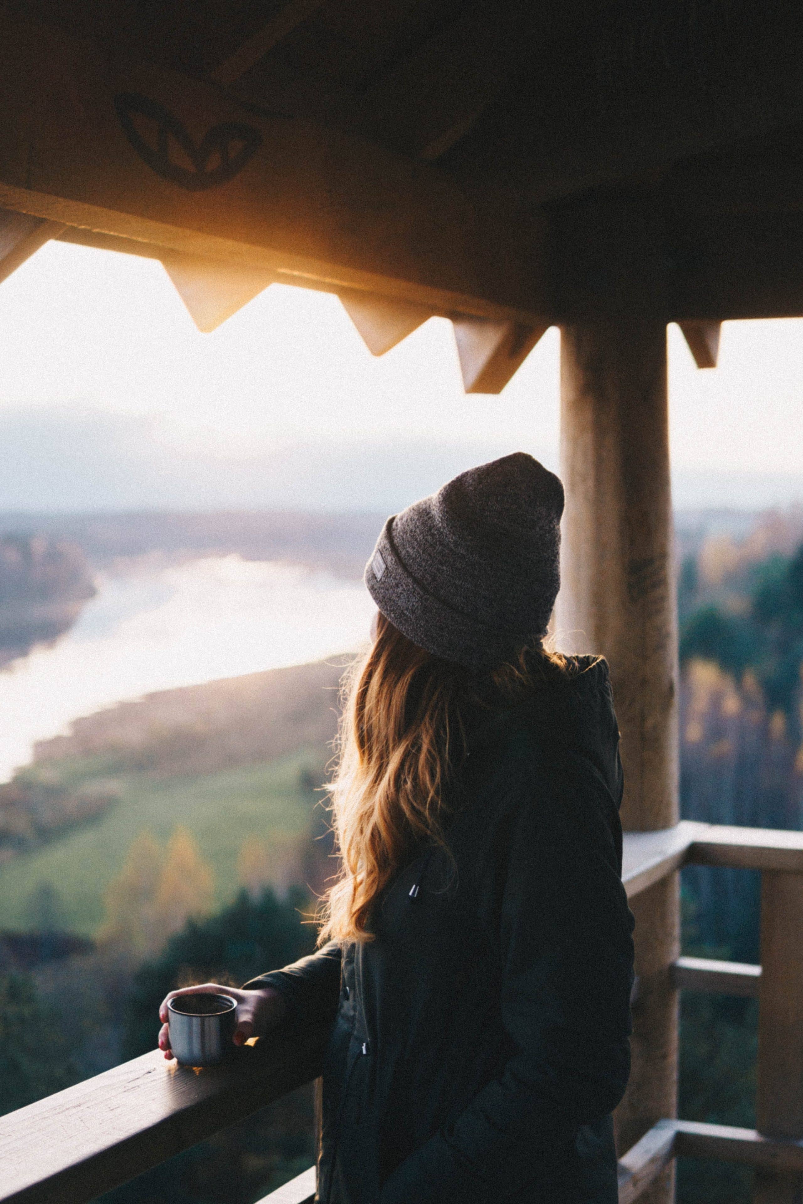 Jeune femme sur le balcon d'un hôtel en train de profiter de la vue sur les montagnes